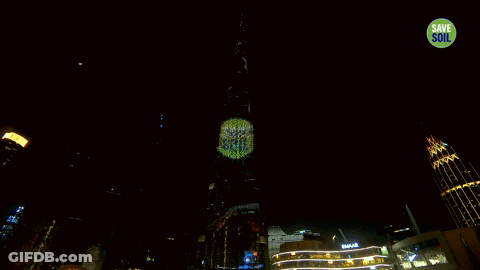 A Very Tall Building Is Lit Up At Night With A Save Soil Sticker On It GIF