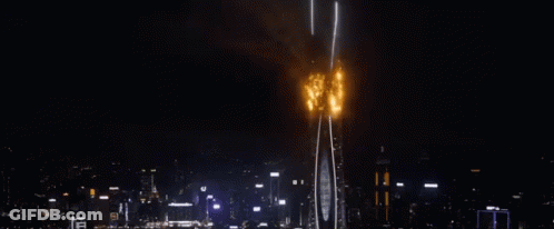 A Very Tall Building Is On Fire In The Middle Of The Night . GIF