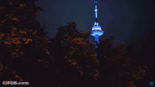 A Very Tall Tower Is Lit Up With Blue Lights GIF