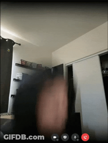 A Video Call Is Taking Place In A Room With A Person 'S Hand In The Foreground GIF