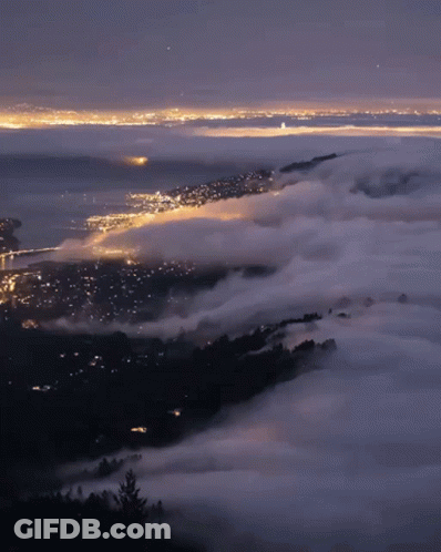 A View Of A City At Night With A Lot Of Clouds GIF