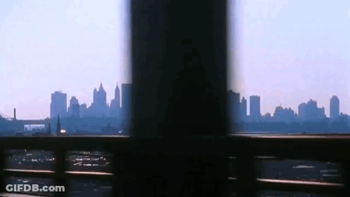 A View Of A City Skyline Through A Fence GIF