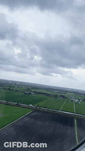 A View Of A Cloudy Sky Over A Lush Green Field GIF