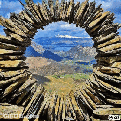 A View Of A Mountain Valley Through A Stone Arch GIF