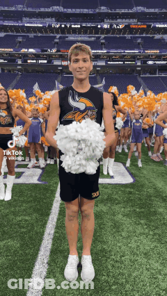 A Vikings Cheerleader Is Holding A Bunch Of Pom Poms On A Field GIF