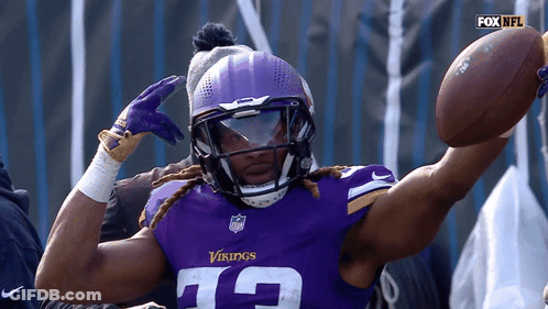 A Vikings Player Wearing A Helmet And Gloves Holds A Football GIF