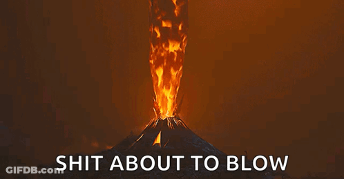A Volcano Is Erupting With A Lot Of Fire Coming Out Of It And The Words `` Shit About To Blow '' Below It . GIF