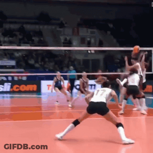 A Volleyball Game Is Being Played In Front Of A Sign That Says ' T.com ' GIF