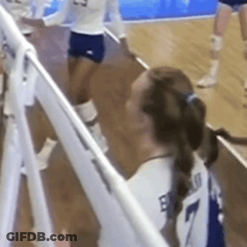 A Volleyball Player Wearing A White Jersey With The Number 7 On It Is Standing Next To A White Fence . GIF
