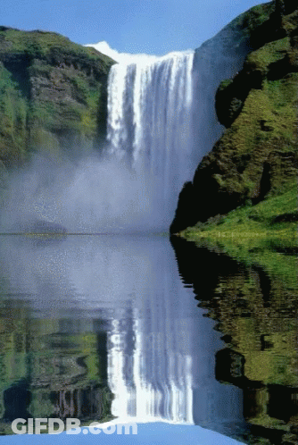 A Waterfall Is Reflected In A Lake Surrounded By Mountains GIF