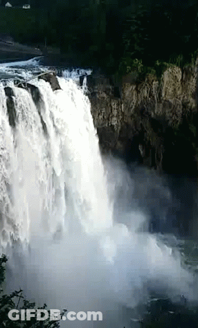A Waterfall Is Surrounded By Trees And A Cliff GIF