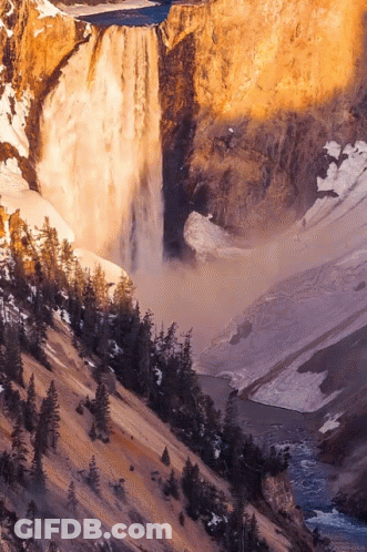 A Waterfall Is Surrounded By Trees And Rocks GIF