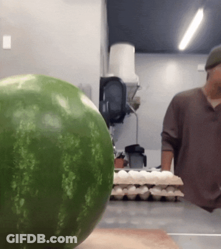 A Watermelon Sits On A Counter Next To A Man GIF