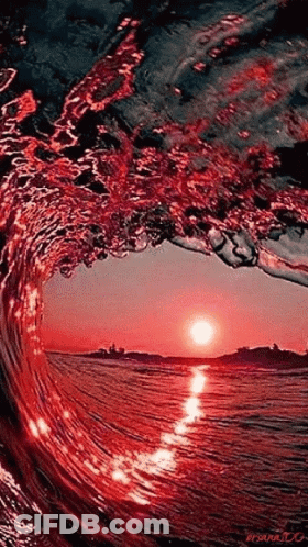A Wave Is Breaking In The Ocean At Sunset And The Sun Is Reflected In The Water GIF