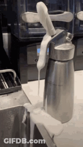 A Whipped Cream Dispenser With A Knife Sticking Out Of It Is On A Counter GIF