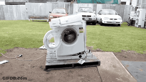 A Whirlpool Washing Machine Sits On A Wooden Pallet Outside GIF