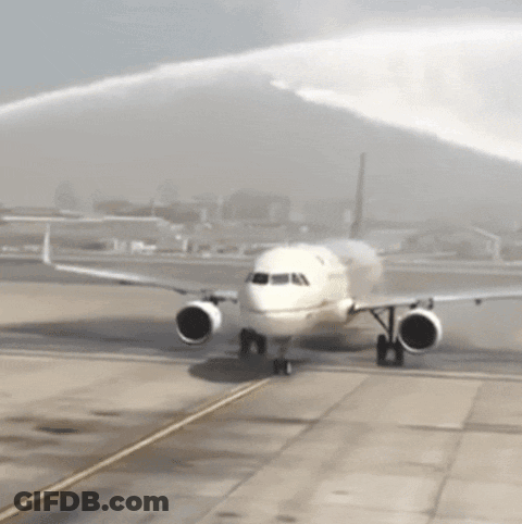 A White Airplane Is Being Sprayed With Water On The Tarmac GIF
