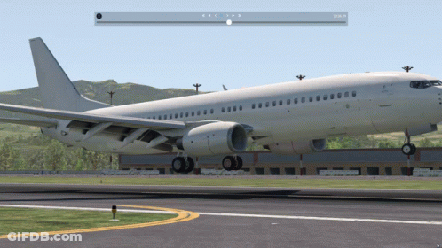 A White Airplane Is Sitting On A Runway With Mountains In The Background And A Pause Button On The Bottom Right GIF