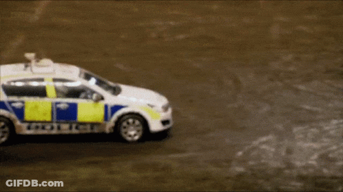 A White And Blue Police Car Is Driving Down A Road GIF