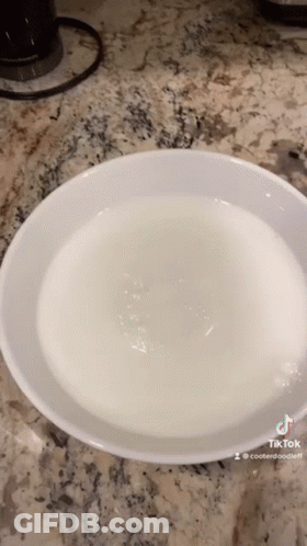A White Bowl Filled With Water Is On A Counter Top . GIF