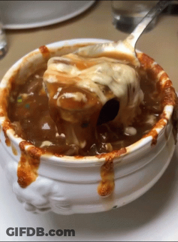 A White Bowl Of Soup With A Spoon In It GIF