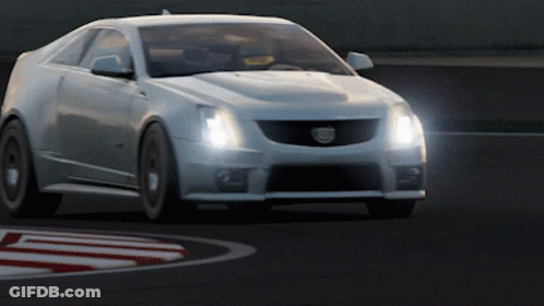 A White Cadillac Is Driving On A Track With Its Headlights On GIF