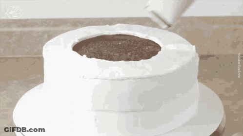 A White Cake With A Hole In The Middle Is Being Frosted GIF