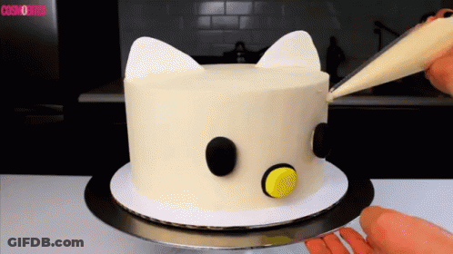 A White Cake With Black Circles And Ears Is Being Decorated By A Person GIF