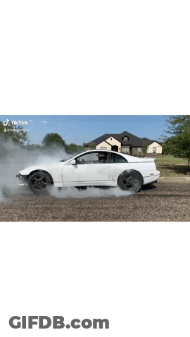 A White Car Is Drifting On A Gravel Road With Smoke Coming Out Of It . GIF