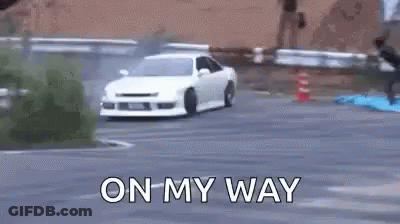 A White Car Is Drifting On A Road With The Words `` On My Way '' Written On The Bottom . GIF