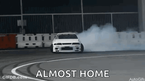 A White Car Is Drifting On A Track And The Words `` Almost Home '' Are Visible . GIF