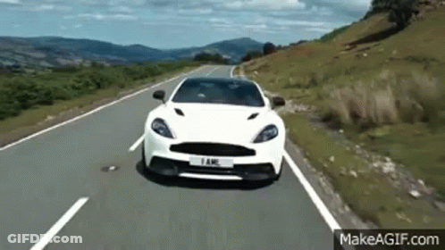 A White Car Is Driving Down A Country Road . GIF