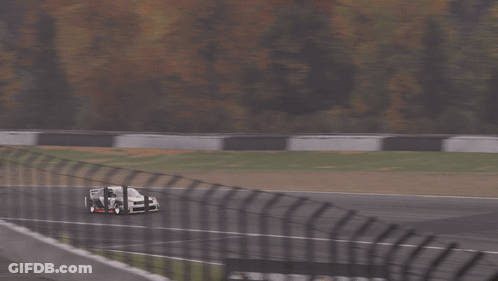 A White Car Is Driving Down A Race Track With Trees In The Background GIF