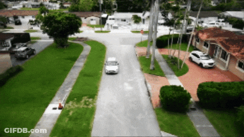 White Car Driving Down Residential Road GIF