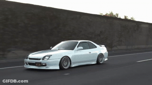A White Car Is Driving Down A Road With A California Tag GIF