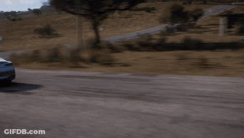 A White Car Is Driving Down A Road With A Grassy Hill In The Background GIF
