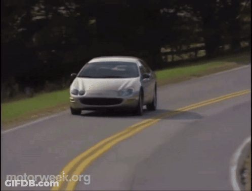 A White Car Is Driving Down A Road With Motorweek.org Written In The Corner GIF