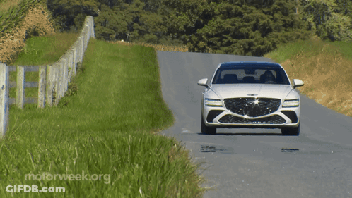 A White Car Is Driving Down A Road With Motorweek.org Written On The Bottom Right GIF