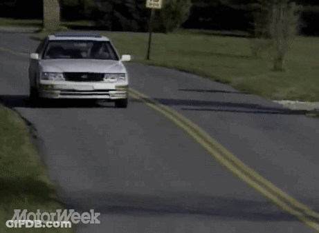 A White Car Is Driving Down A Road With Motorweek Written In The Corner GIF