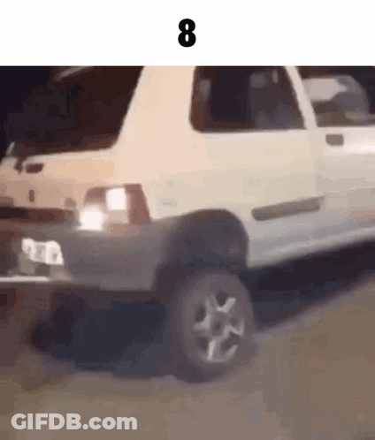 A White Car Is Driving Down A Road With The Number 8 On The Bottom Of It . GIF