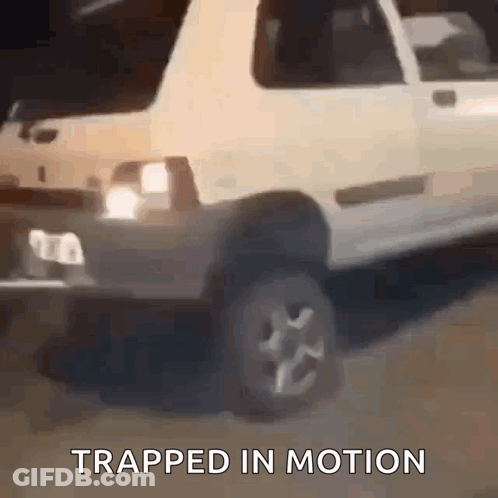 A White Car Is Driving Down A Road With The Words Trapped In Motion Written Below It . GIF