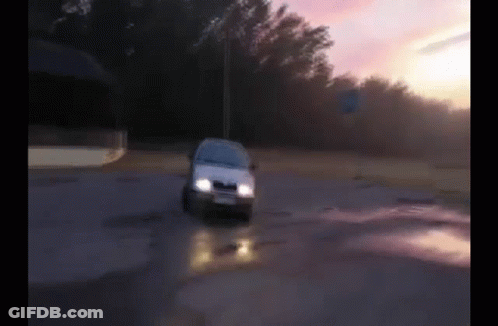 A White Car Is Driving Down A Road With Trees In The Background GIF