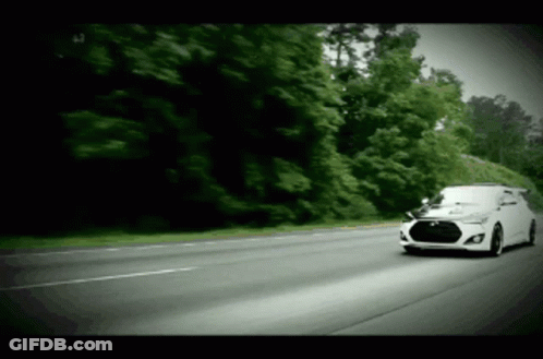 A White Car Is Driving Down A Road With Trees On The Side GIF