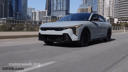 A White Car Is Driving On A Highway With Motorweek.org Written In The Corner GIF
