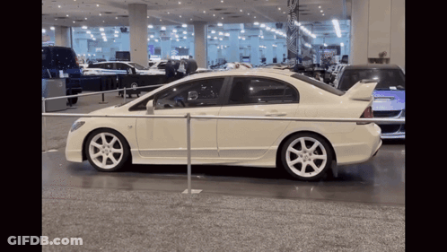 A White Car Is Parked Behind A Metal Barrier GIF