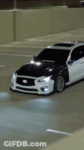 A White Car Is Parked In A Parking Lot With A Black Hood GIF