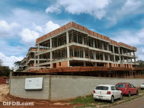 A White Car Is Parked In Front Of A Building Under Construction That Says Bgr GIF