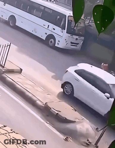 A White Car Is Parked On The Side Of The Road Next To A White Bus With The Letters Tb On The Front GIF