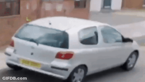 A White Car Is Parked On The Side Of The Road GIF