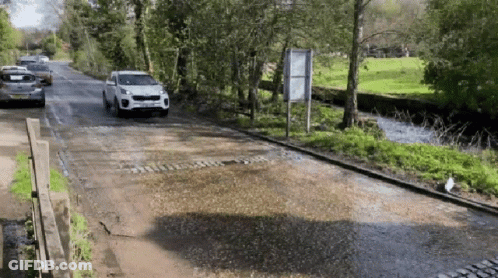 A White Car With A License Plate That Says ' Jcw ' On It Is Driving Down A Road GIF